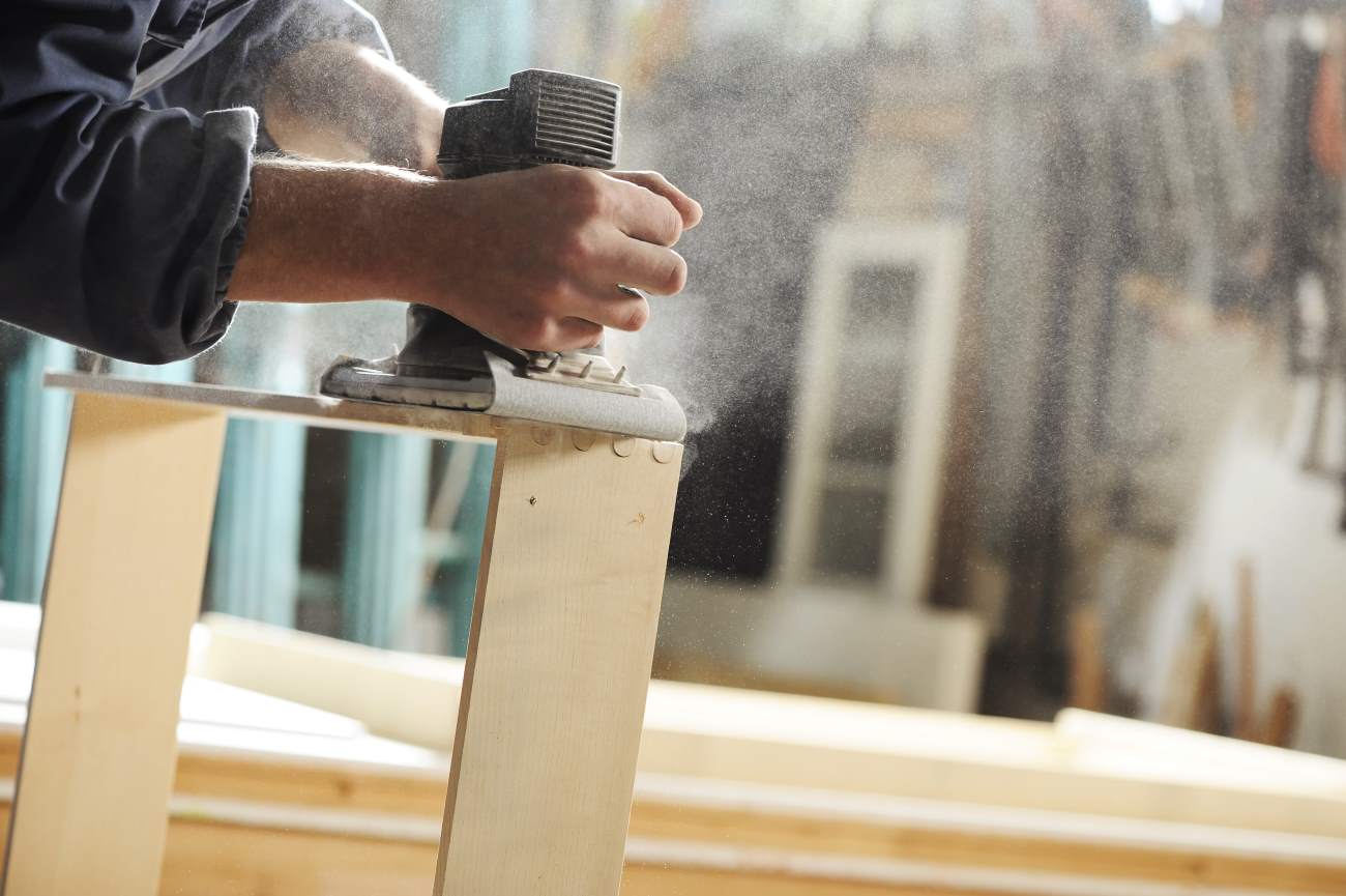 Carpenter working on a piece of furniture with a planer.